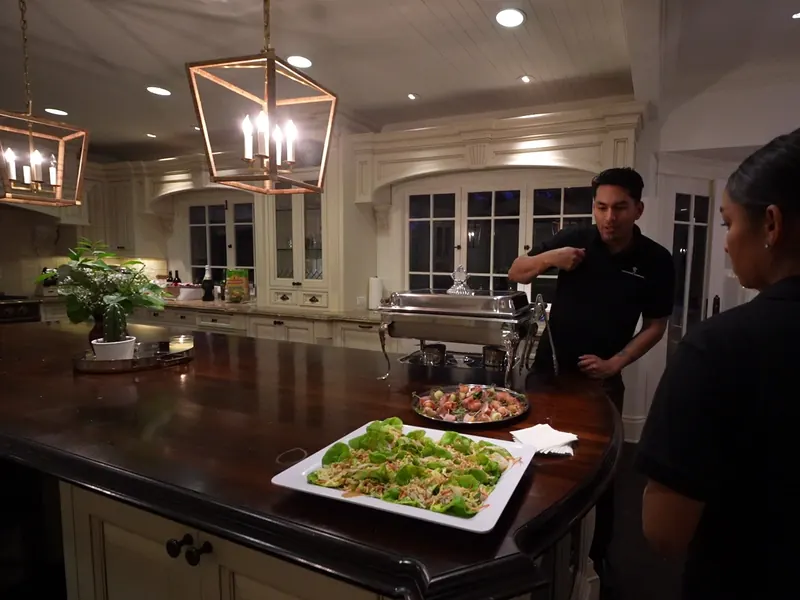 Staff plating platters on a kitchen island during a Pleasant Hill dinner