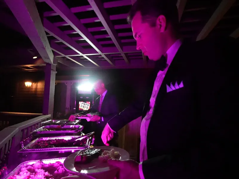 Server tending a chafing-dish buffet under evening lights at a Lafayette party