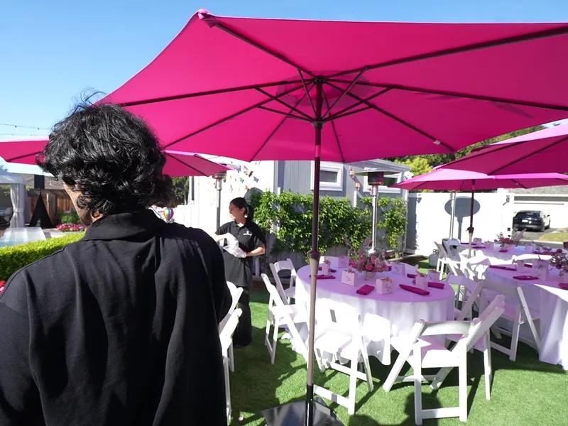 White folding chairs and umbrella tables on a Pleasant Hill backyard lawn