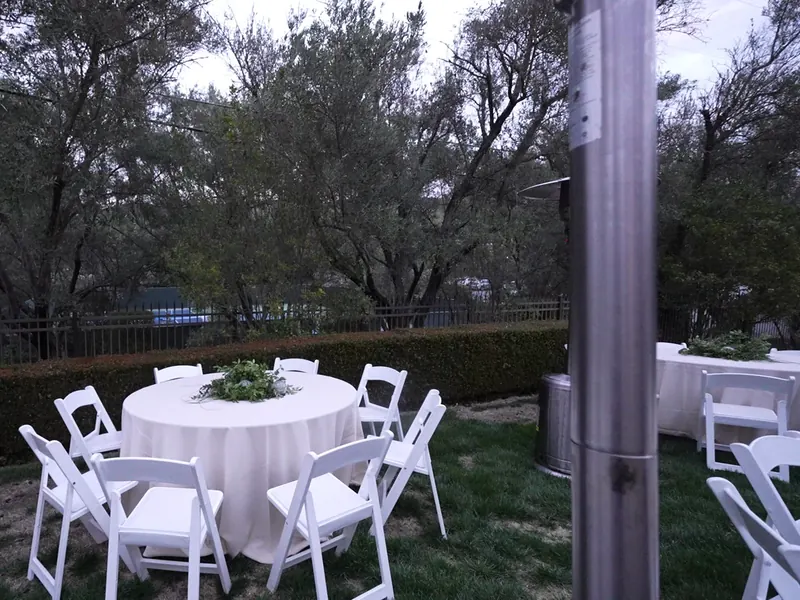 Round table with white chairs shaded by oaks at an Orinda home