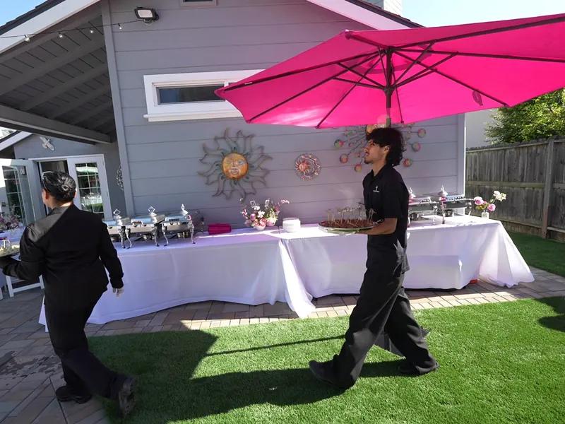 Catering staff setting a linen buffet table on a Martinez lawn