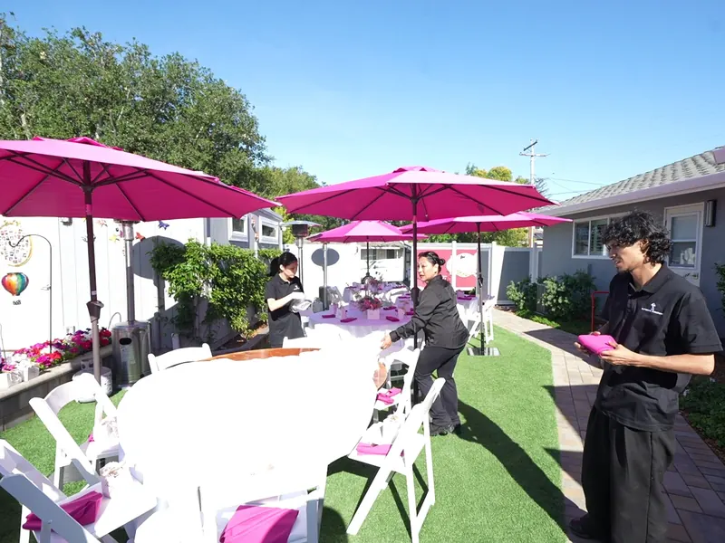 Server with a tray moving between backyard tables in Clayton