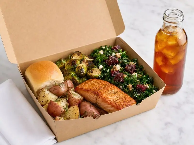 Walnut Creek boxed catering entrée served with baked salmon, rosemary potatoes, caramelized Brussels sprouts, fresh salad, and iced tea.
