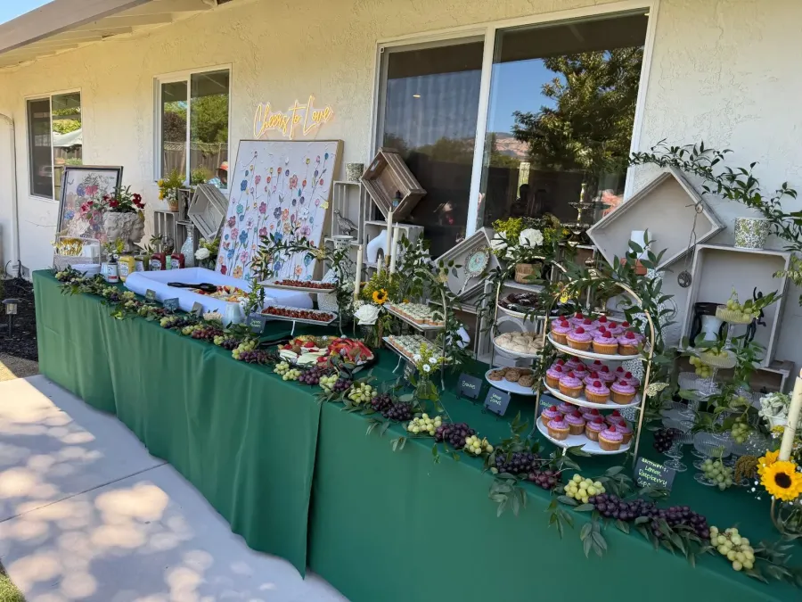 Shower sweets and grazing spread softened with roses and greenery tucked between cupcakes and fruit — floral shower styling for Danville catering