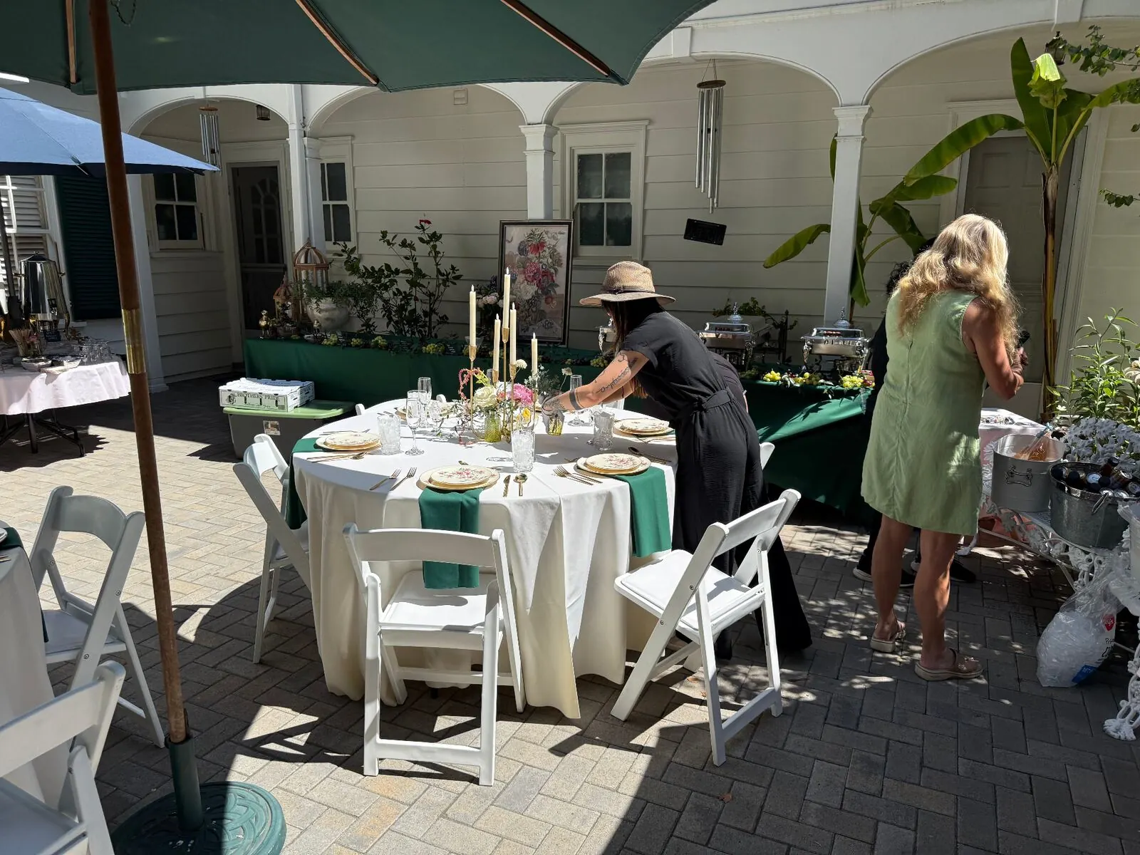Courtyard rounds in emerald linens finished with compact centerpieces, stemware and full place settings — floral and rental styling from Pleasant Hill catering