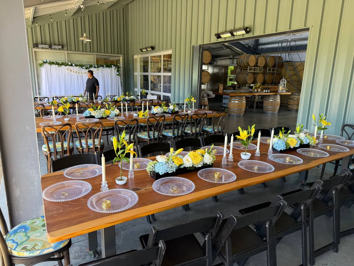 Banquet table carrying lily, hydrangea and rose arrangements between slim tapers down its length — centerpiece design for Contra Costa County receptions