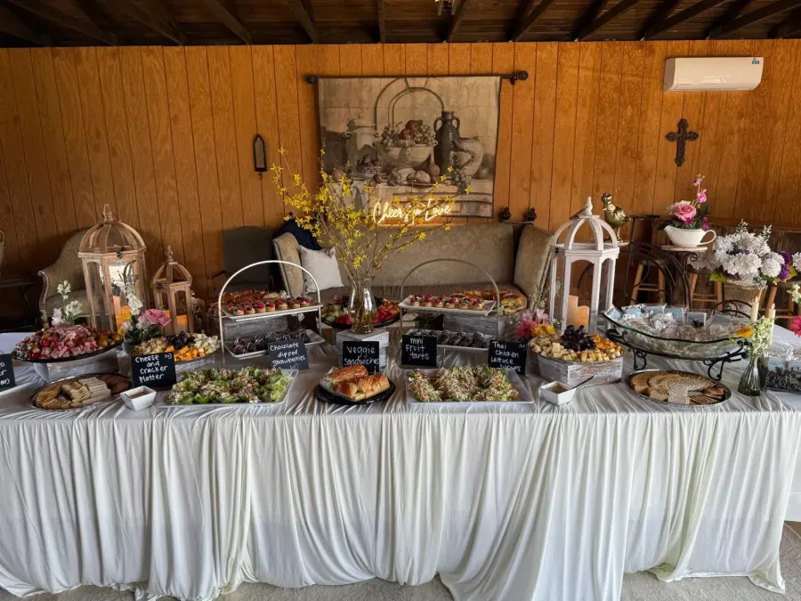 Grazing table of cured meats, tea sandwiches and fruit tarts punctuated with low bud vases along its length — floral-styled grazing tables for Lafayette catering