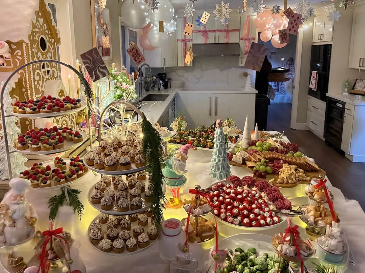 Themed party tablescape where tiered tarts and cupcakes sit beneath pastel balloons with fresh blossom accents tucked between them — floral party styling for Concord catering celebrations